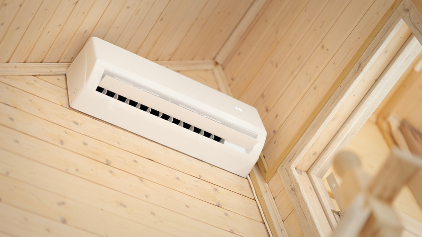 White air conditioner on the wall of a wooden house. Split air conditioner